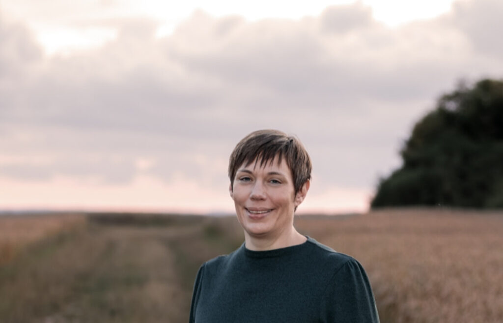 Frau steht ruhig in der Natur und blickt in den Sonnenuntergang – Symbol für Hoffnung und innere Ruhe beim Überwinden von Selbstzweifeln.